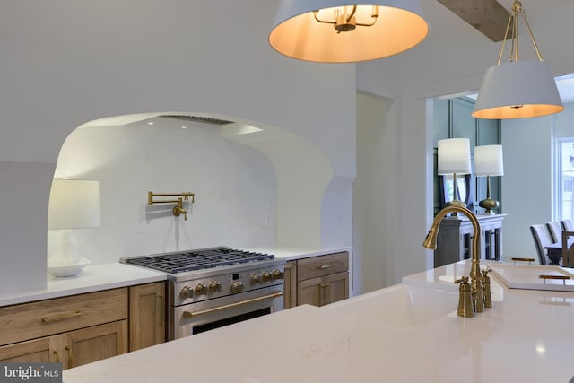 kitchen featuring tasteful backsplash, stainless steel stove, sink, and pendant lighting