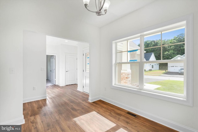 unfurnished room featuring a notable chandelier and dark hardwood / wood-style floors