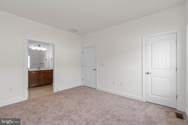 unfurnished bedroom featuring sink, light carpet, and ensuite bathroom