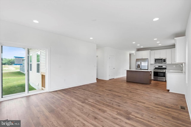 kitchen featuring white cabinets, hardwood / wood-style flooring, stainless steel appliances, sink, and a center island