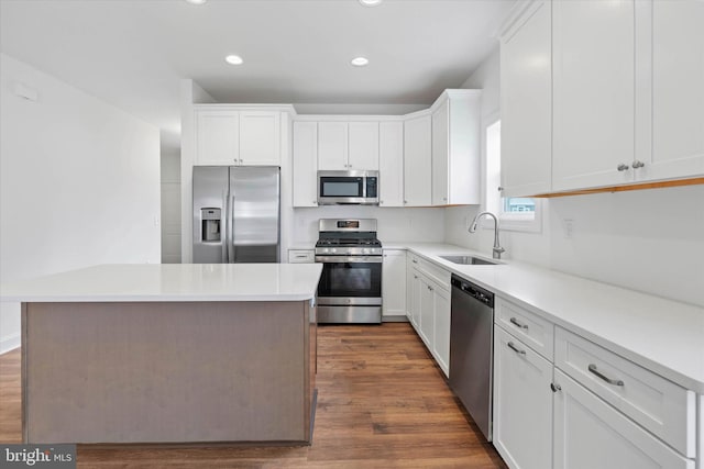 kitchen featuring dark hardwood / wood-style flooring, appliances with stainless steel finishes, white cabinetry, sink, and a center island