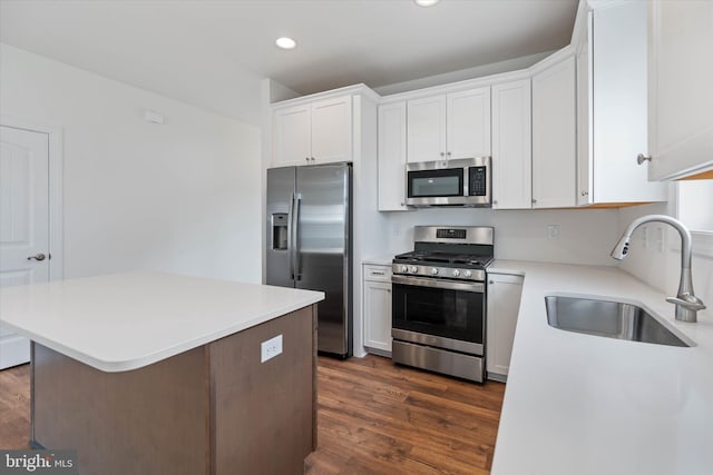 kitchen with sink, appliances with stainless steel finishes, white cabinetry, and dark hardwood / wood-style flooring