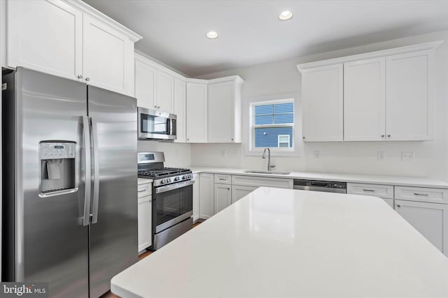 kitchen with appliances with stainless steel finishes, white cabinetry, and sink