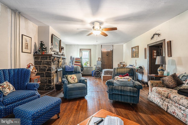 living room featuring ceiling fan, a fireplace, dark hardwood / wood-style flooring, and radiator heating unit