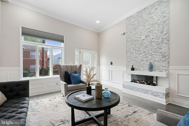 living room with a fireplace, wood-type flooring, and ornamental molding