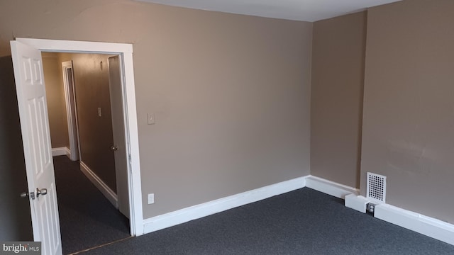 spare room featuring dark carpet