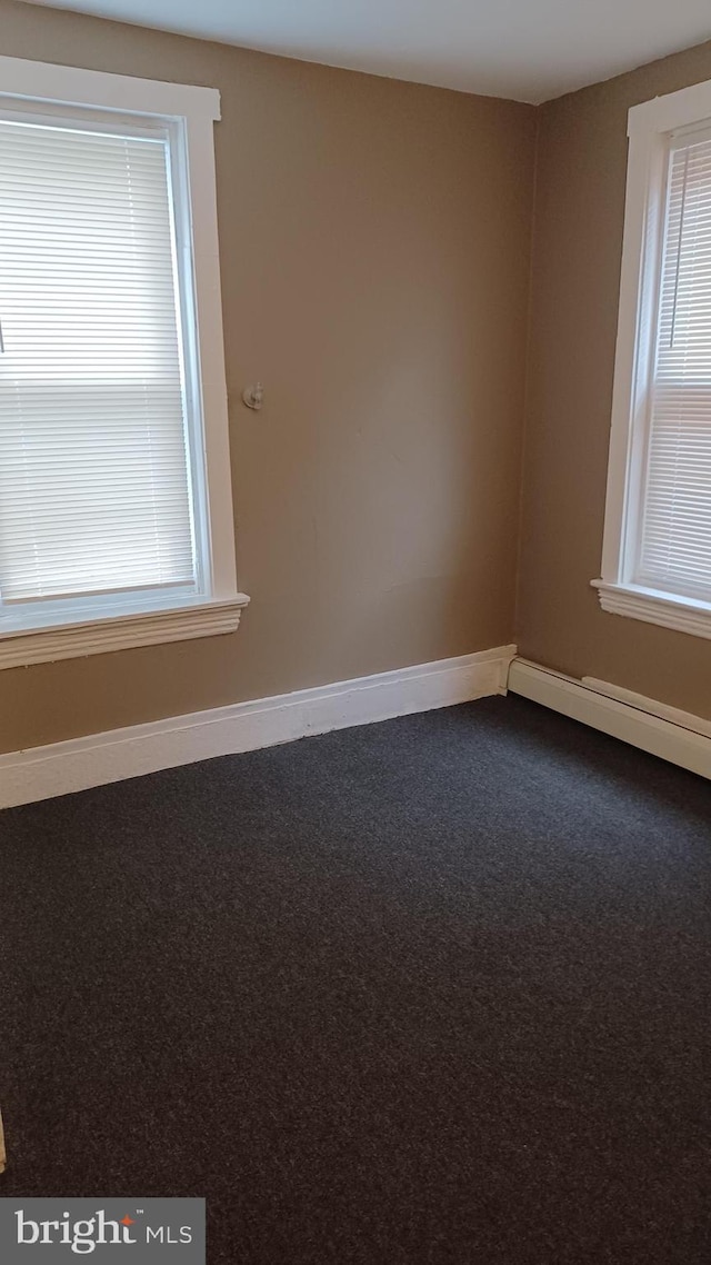 carpeted spare room featuring a baseboard radiator and a wealth of natural light