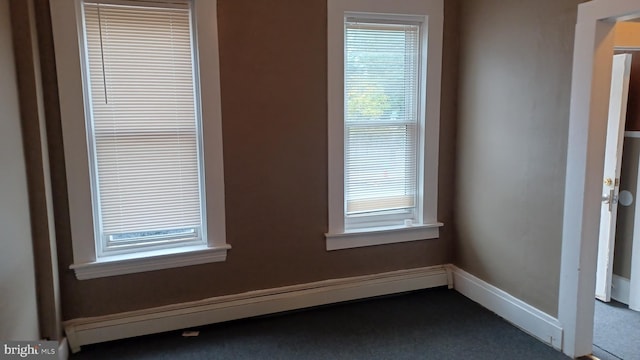 carpeted empty room with a baseboard radiator