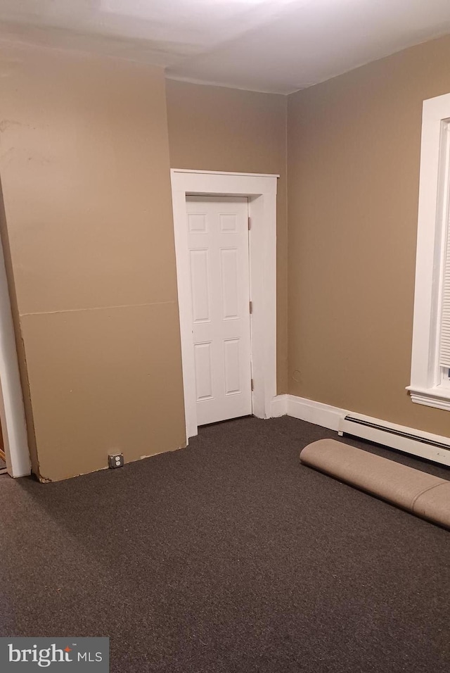 carpeted spare room featuring a baseboard heating unit