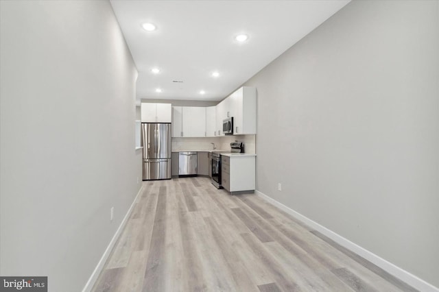 kitchen with white cabinetry, backsplash, appliances with stainless steel finishes, and light wood-type flooring