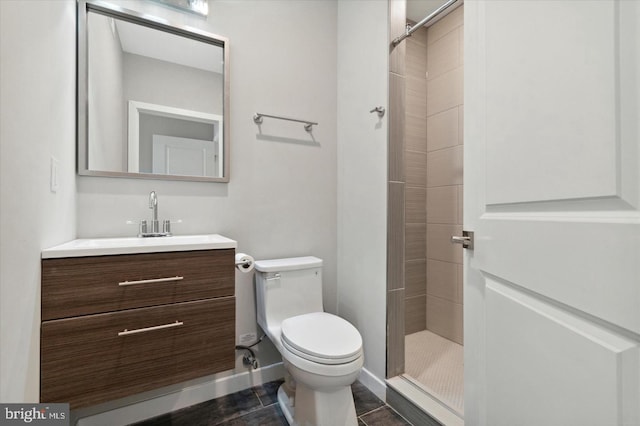 bathroom featuring vanity, a tile shower, toilet, and tile patterned floors