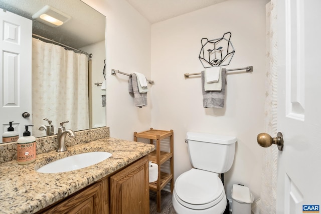 bathroom with vanity, toilet, and a textured ceiling