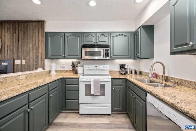 kitchen featuring light hardwood / wood-style flooring, stainless steel appliances, sink, light stone countertops, and a textured ceiling