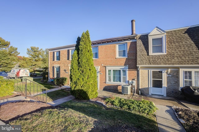 view of property featuring a front yard and central AC