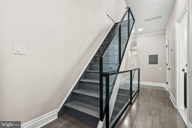 staircase featuring electric panel and wood-type flooring