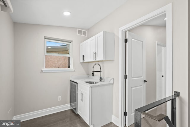 clothes washing area featuring dark hardwood / wood-style floors, beverage cooler, and sink