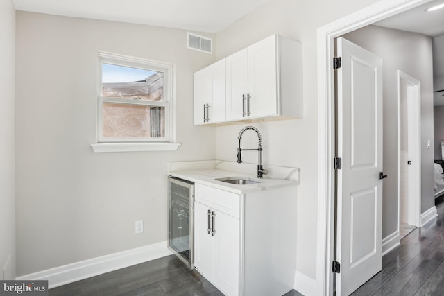 bar with dark wood-type flooring, lofted ceiling, white cabinets, sink, and wine cooler