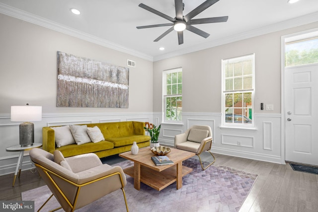 living room featuring a wealth of natural light, wood-type flooring, ceiling fan, and crown molding