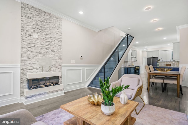 living room featuring ornamental molding, a large fireplace, and wood-type flooring