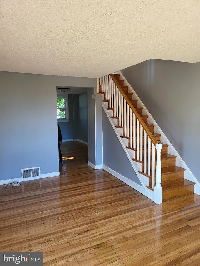 stairs featuring hardwood / wood-style floors and a textured ceiling