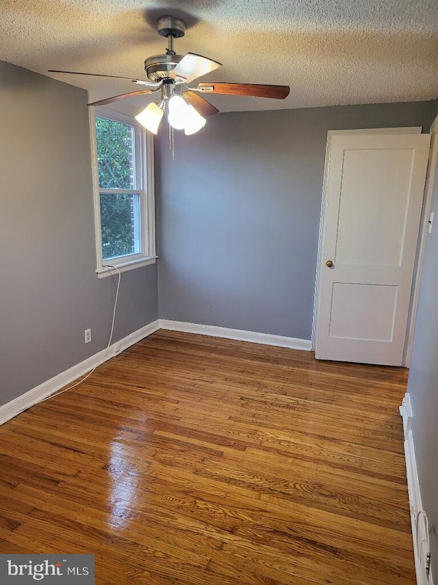 empty room with ceiling fan, light hardwood / wood-style flooring, and a textured ceiling