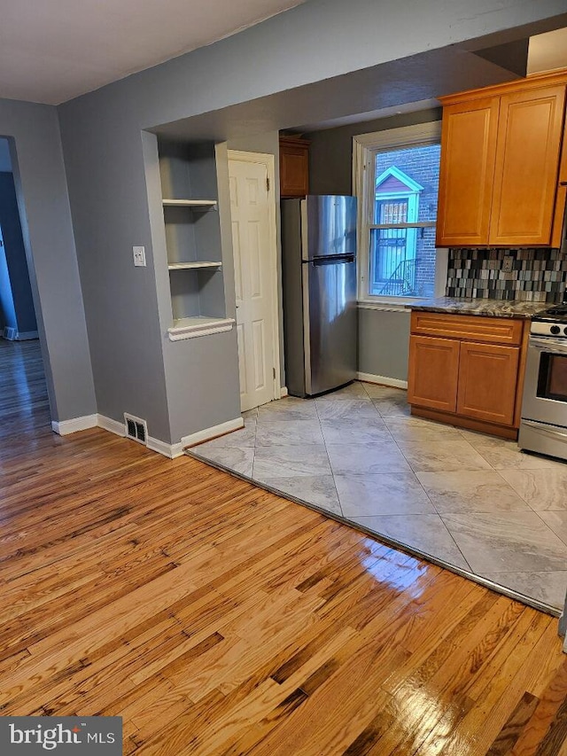 kitchen with decorative backsplash, built in features, light wood-type flooring, and stainless steel appliances