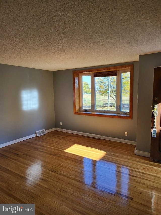 unfurnished room with wood-type flooring and a textured ceiling