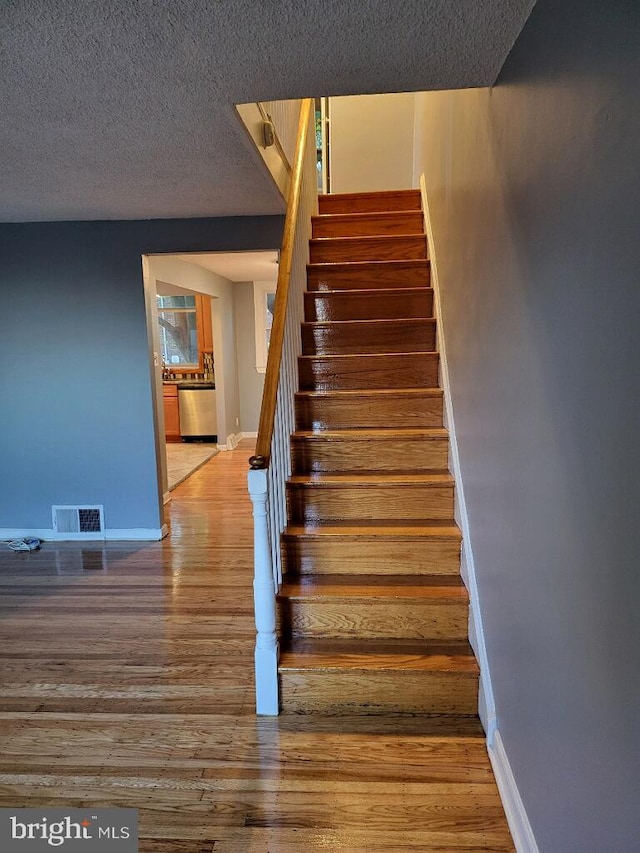 stairway featuring wood-type flooring and a textured ceiling