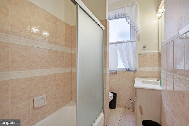 full bathroom featuring bath / shower combo with glass door, tile walls, toilet, vanity, and tile patterned flooring