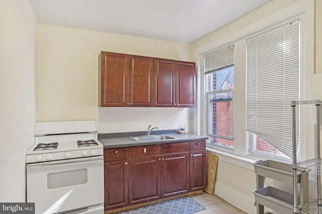 kitchen with sink, light tile patterned flooring, and white gas range