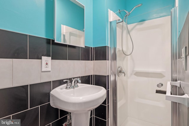 bathroom featuring walk in shower, sink, tile walls, and backsplash