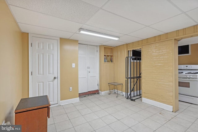 interior space with tile patterned floors, wooden walls, and a paneled ceiling