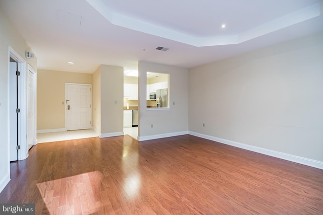 spare room with wood-type flooring and a tray ceiling