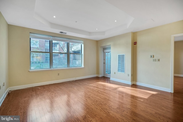 empty room featuring hardwood / wood-style flooring and a raised ceiling