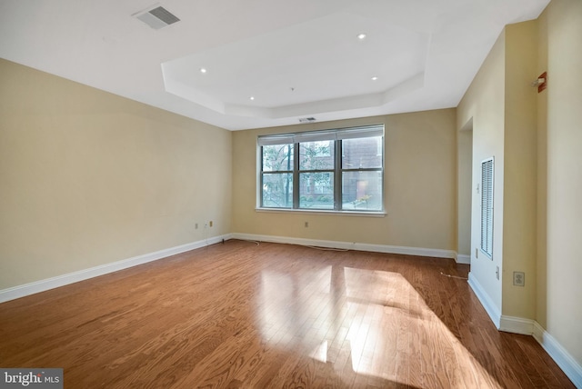 spare room with a raised ceiling and hardwood / wood-style floors