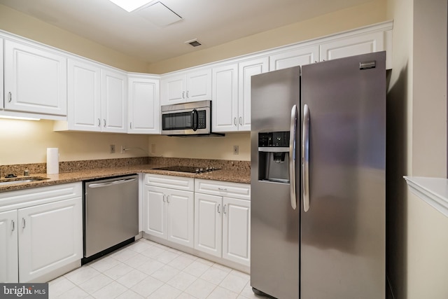 kitchen with dark stone countertops, appliances with stainless steel finishes, and white cabinets