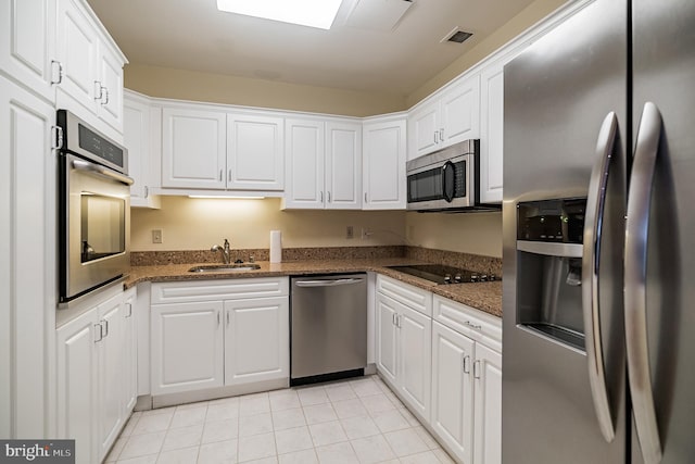 kitchen featuring sink, white cabinetry, stainless steel appliances, and dark stone countertops