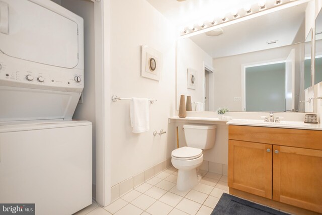 bathroom with vanity, stacked washer and dryer, toilet, and tile patterned flooring