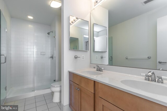 bathroom with a shower with door, vanity, toilet, and tile patterned flooring