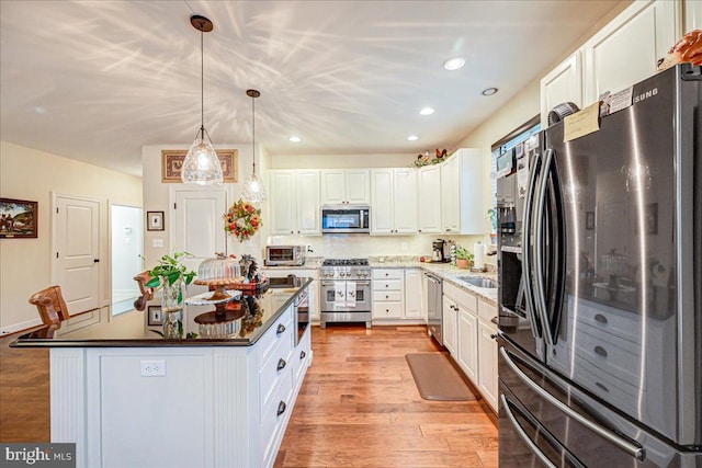 kitchen with appliances with stainless steel finishes, white cabinets, a center island, and light wood-type flooring