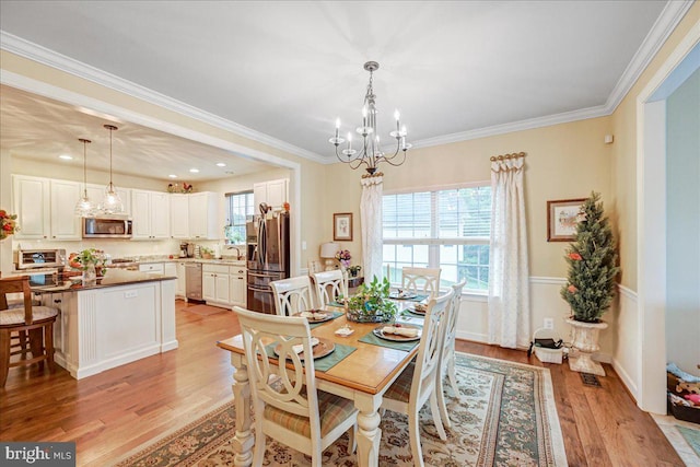 dining space featuring sink, crown molding, and light hardwood / wood-style floors