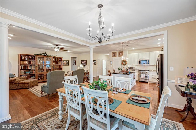 dining area with ornate columns, light hardwood / wood-style floors, ornamental molding, and ceiling fan with notable chandelier