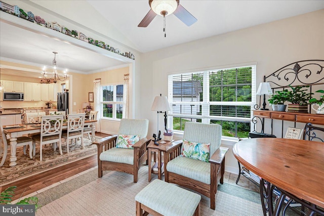 sitting room with ornamental molding, vaulted ceiling, ceiling fan with notable chandelier, and light hardwood / wood-style floors