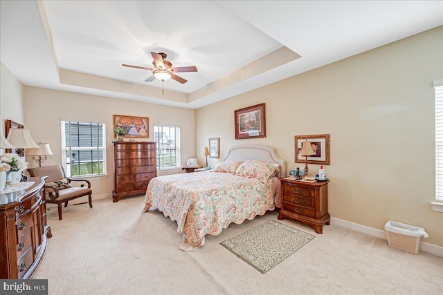 carpeted bedroom featuring a tray ceiling and ceiling fan