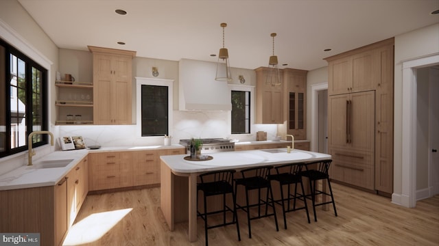 kitchen featuring a kitchen island with sink, decorative light fixtures, sink, custom exhaust hood, and light brown cabinets