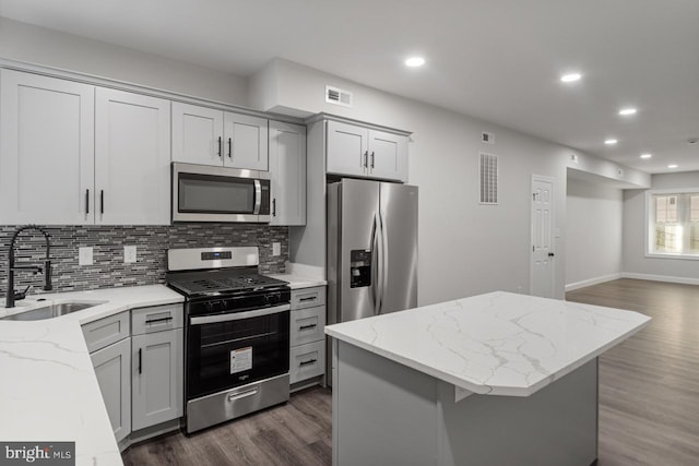 kitchen featuring gray cabinetry, appliances with stainless steel finishes, sink, dark hardwood / wood-style flooring, and light stone counters