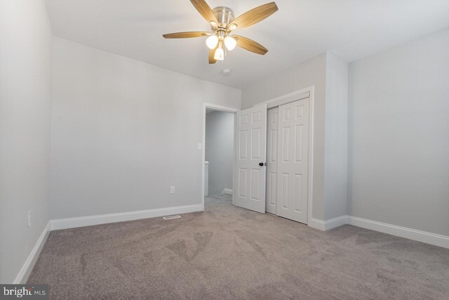 unfurnished bedroom featuring a closet, ceiling fan, and light carpet