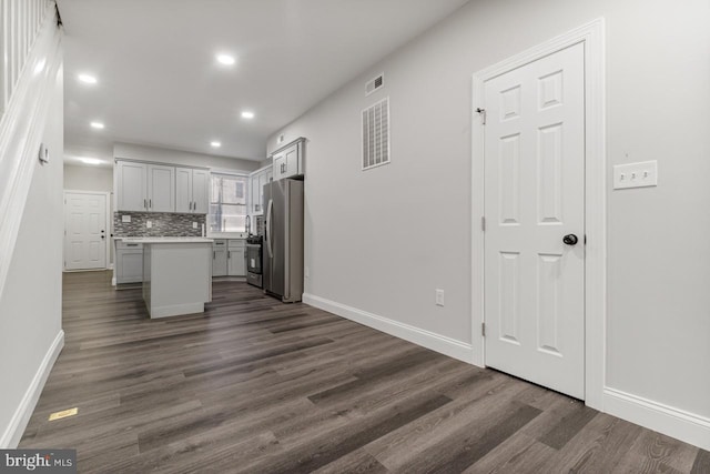 kitchen with dark wood-type flooring, stainless steel refrigerator, and a kitchen island