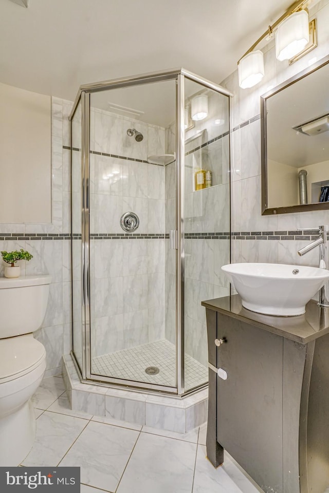 bathroom featuring tile walls, vanity, toilet, and walk in shower