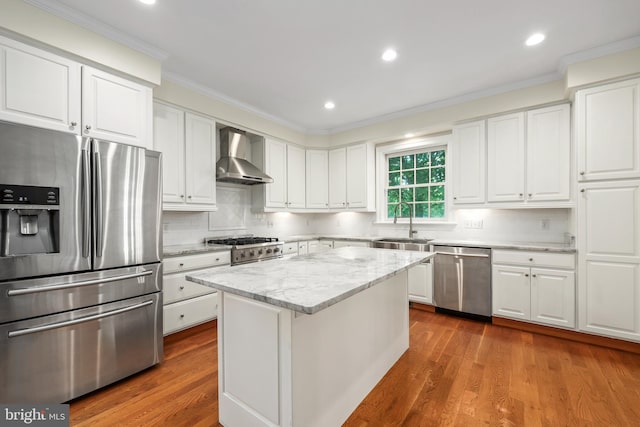 kitchen featuring wall chimney range hood, white cabinetry, stainless steel appliances, and wood-type flooring